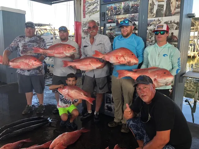 Group of anglers including a young boy with red snapper at the dock after a trip